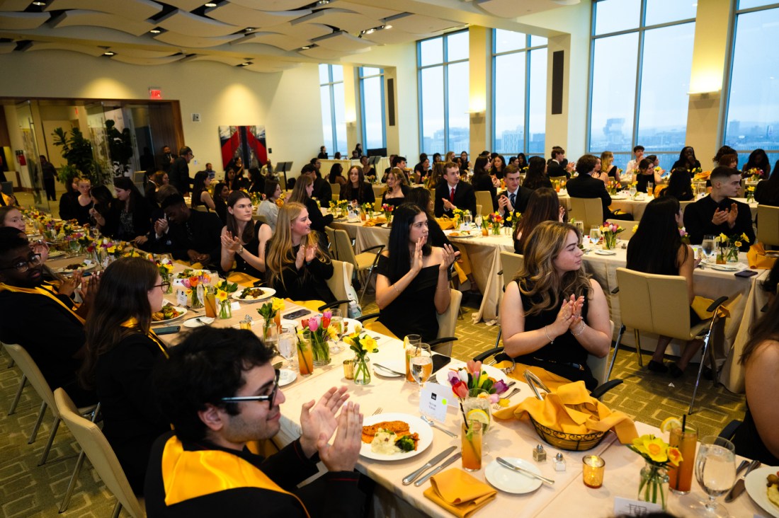 Huntington 100 Inductees sitting at rows of long tables all clapping.