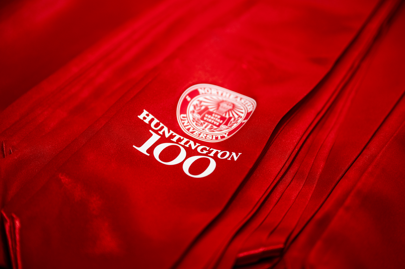 Stacks of Northeastern branded red sashes that say 'Huntington 100' on them.