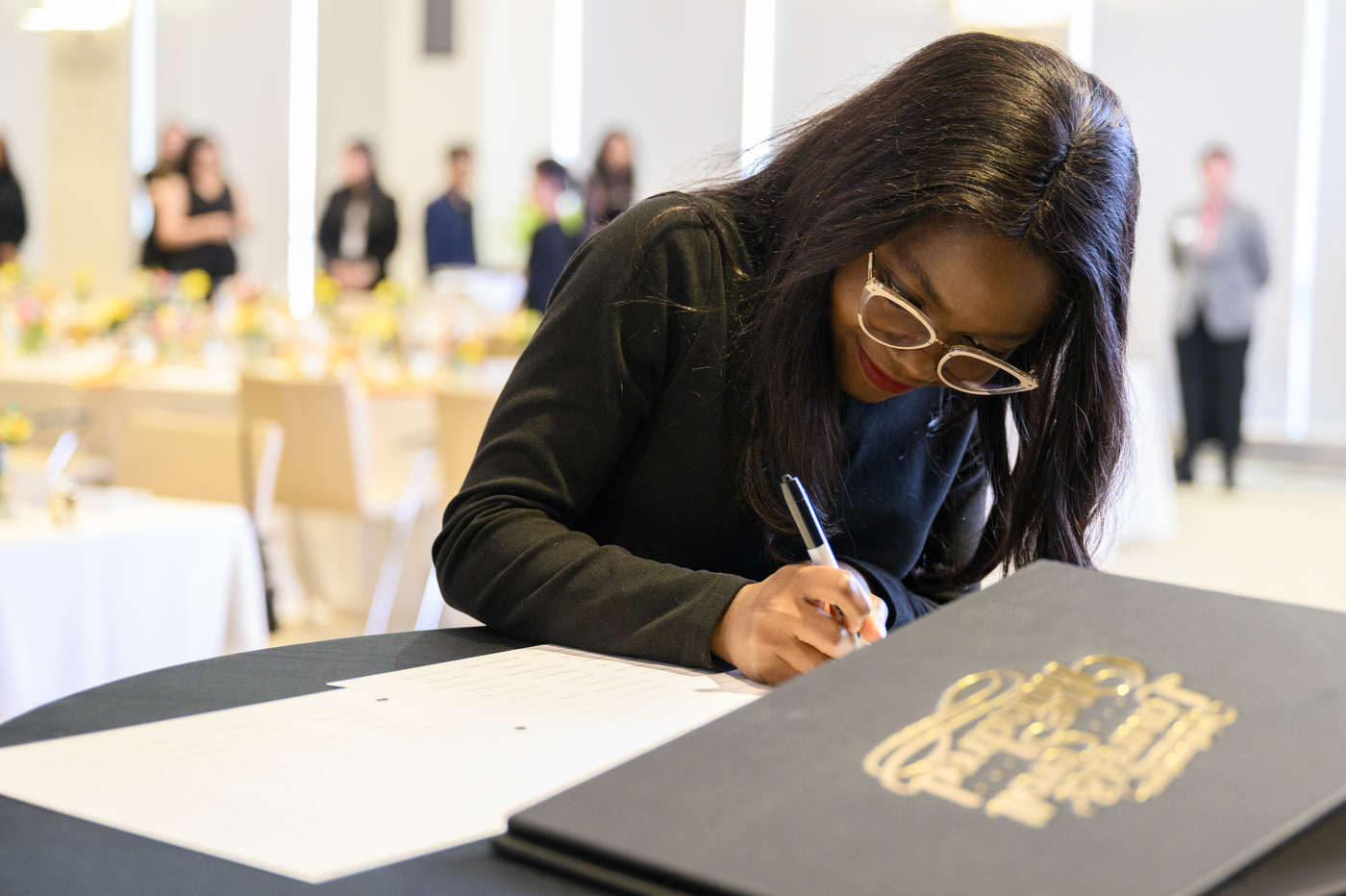 A member of the Northeastern Community signing a piece of paper at the Laurel & Scroll Induction Ceremony.