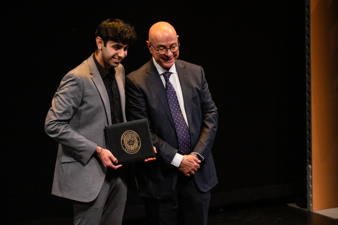 President Aoun posing on stage with a student receiving an honors.
