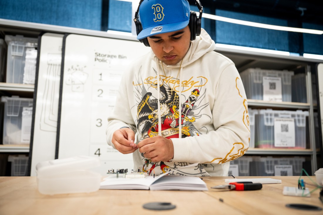 Jared Perkins looking at a book on a table in the EXP Makerspace.