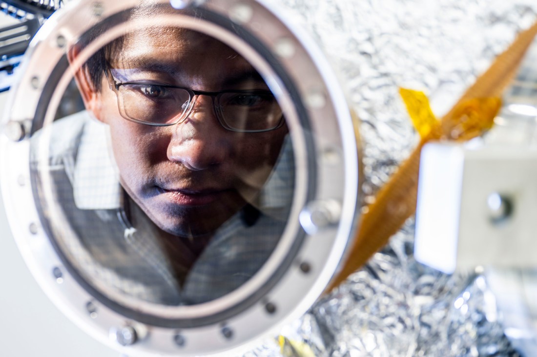 Kin Chung Fong working in the lab, gazing intently at a reflective surface.