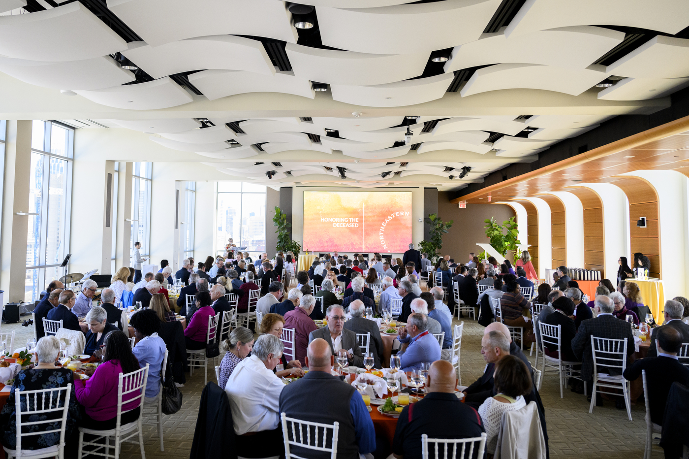 A room full of people sitting at round tables for the 25 Year Associates Brunch.