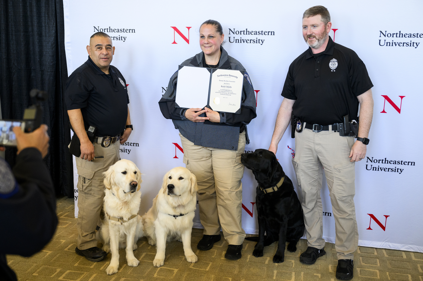 Three NUPD officers posing with Northeastern community resource dogs at the 25 Year Associates Brunch.