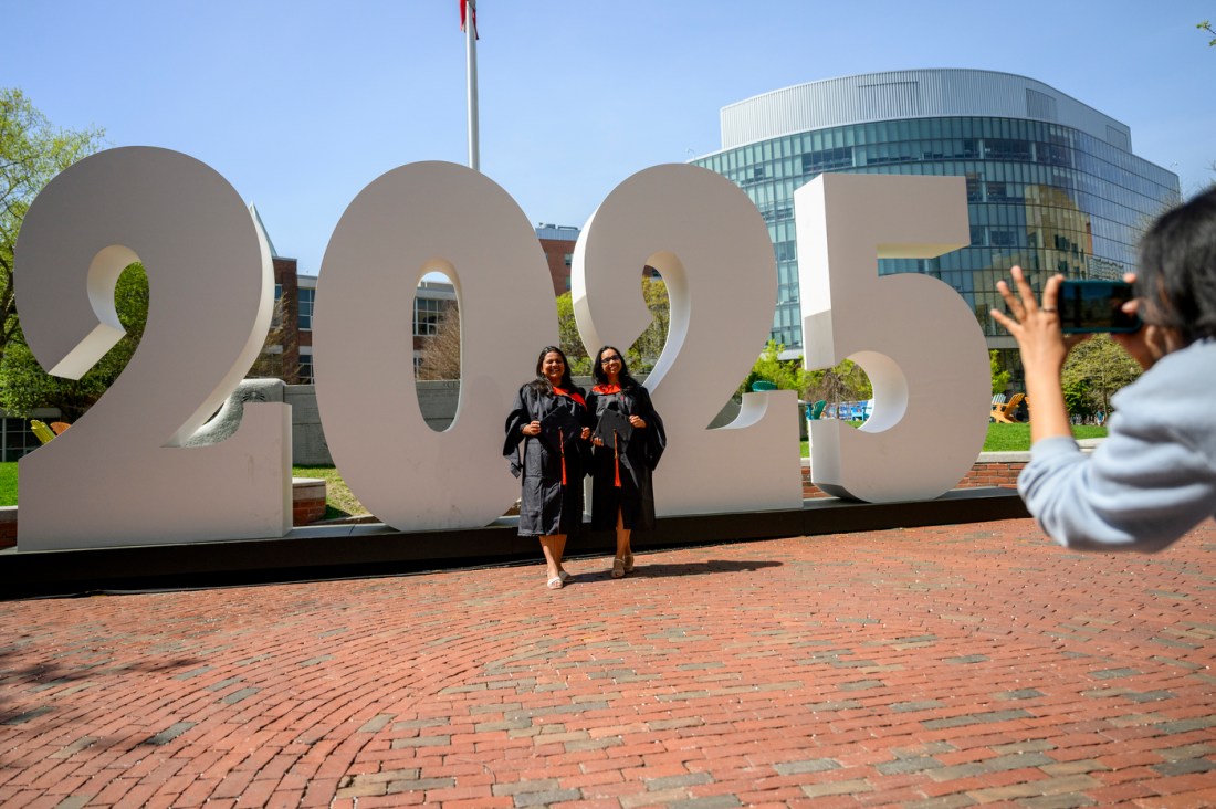 Two Northeastern graduates posing for a photo in front of a large '2025' sign.