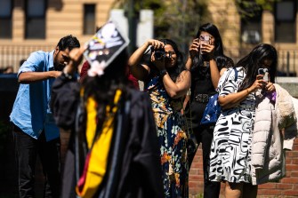 Several people taking photographs of a Northeastern graduate.