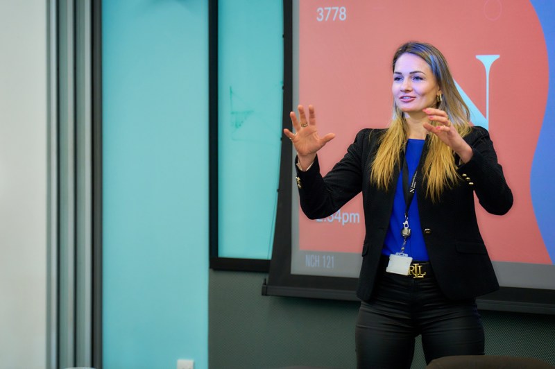 A person wearing a blue shirt and black blazer presenting at a Northeastern psychology conference.