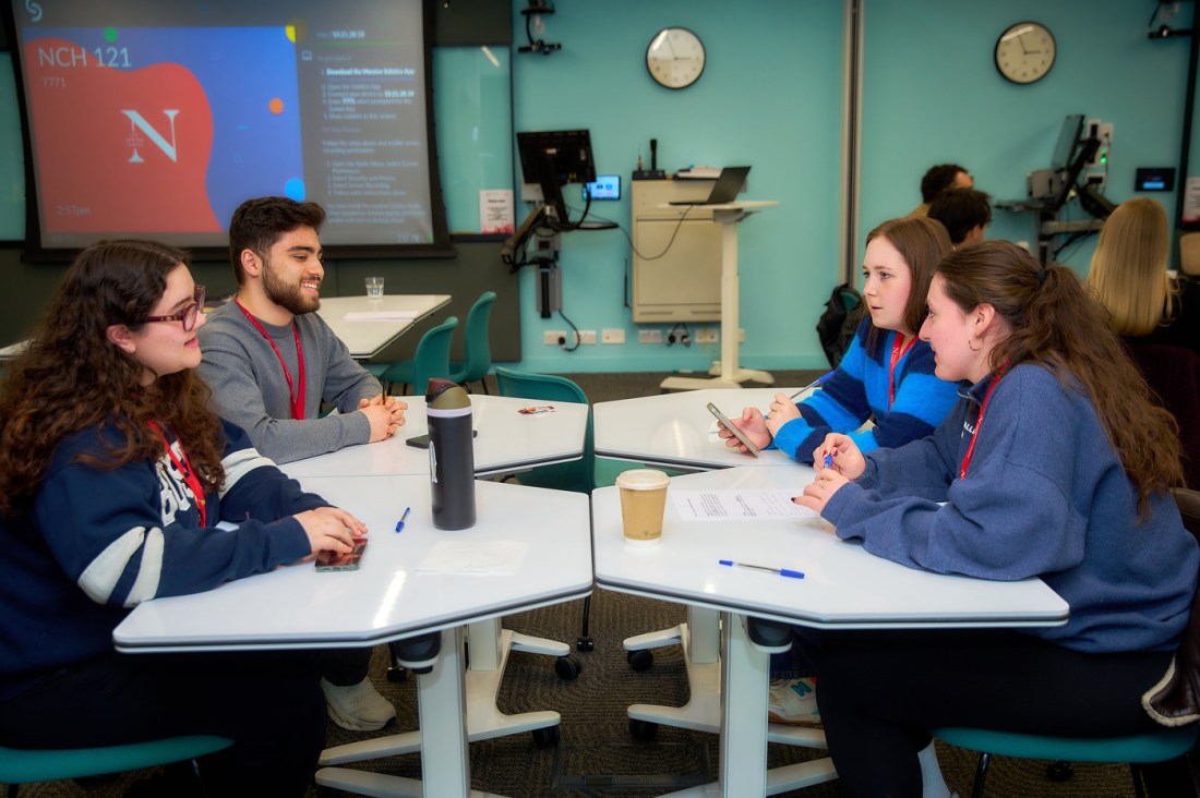 Members of the Northeastern community sitting around a table talking to each other.