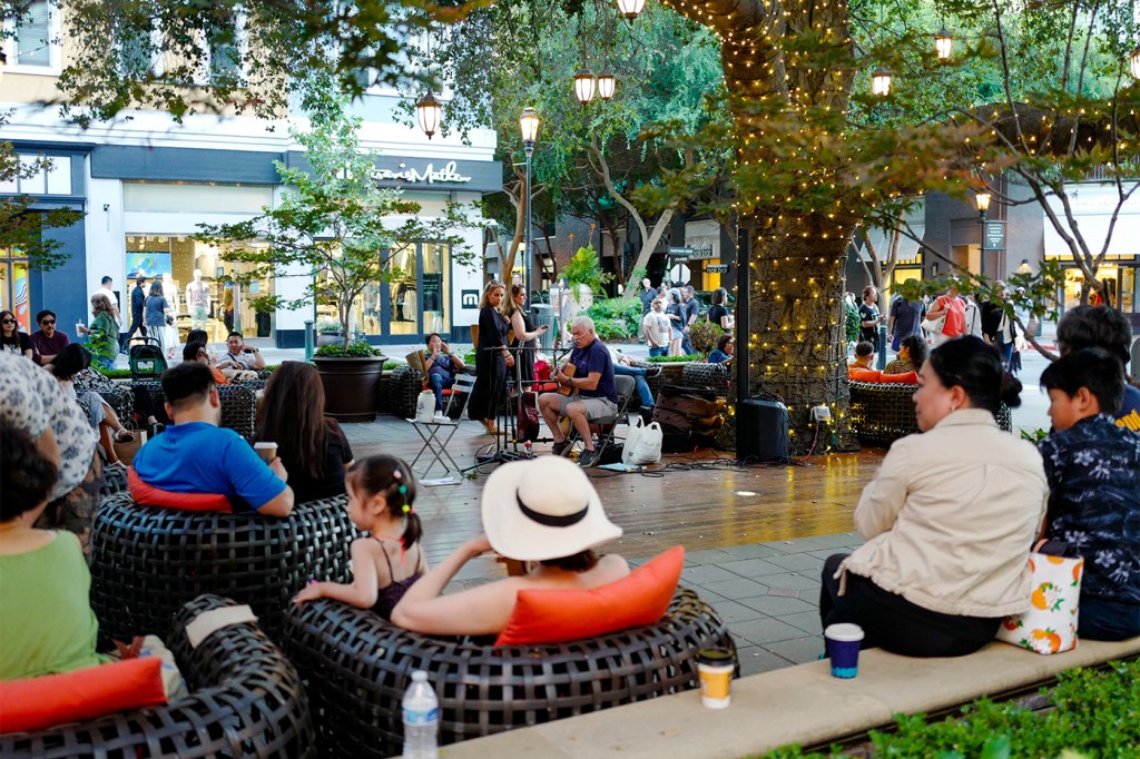 People sitting outside enjoying an outdoor performance.