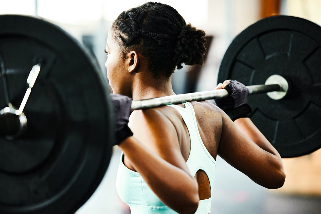 A person squatting with a barbell with two plates on either side at the gym.