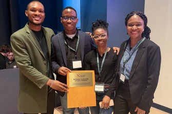 Four people posing with an award plaque.