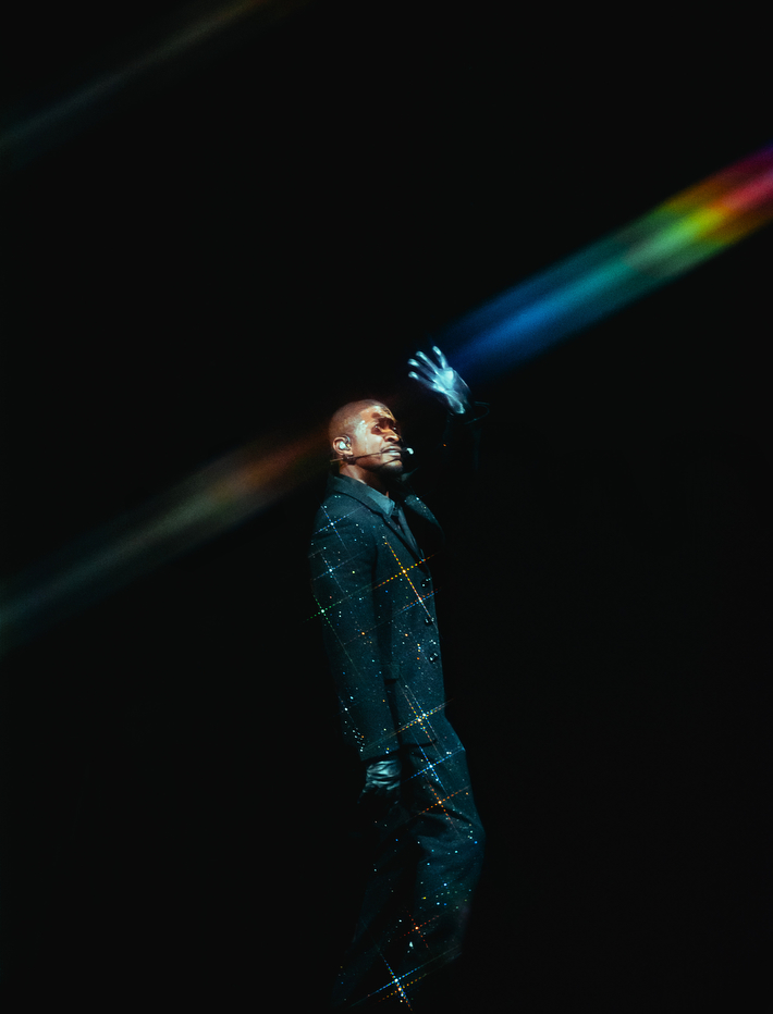 Kendrick Lamar stands under a spotlight during a dramatic concert moment.
