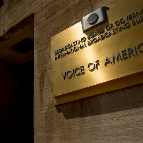 A gold sign on a building that says 'Voice of America' on it.
