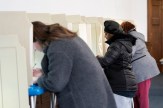 Three people marking their ballot while voting.