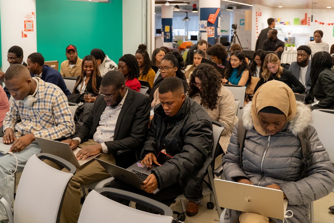 Students sitting in rows in a room working on their laptops.