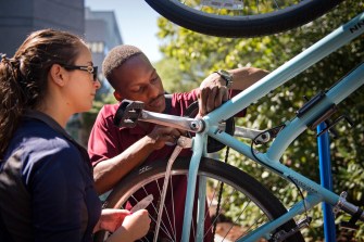 Two people working on a bicycle.