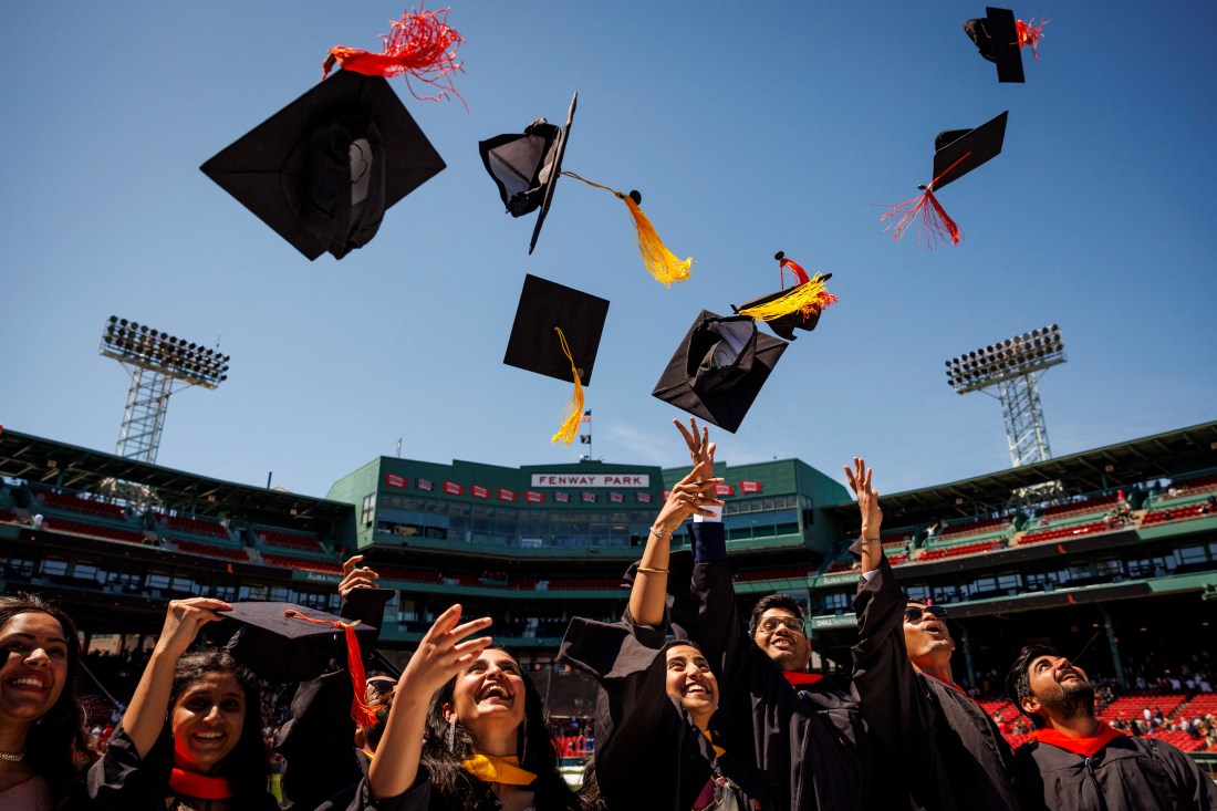 Graduates throw caps in the air at Fenway Park during Northeastern’s Commencement.