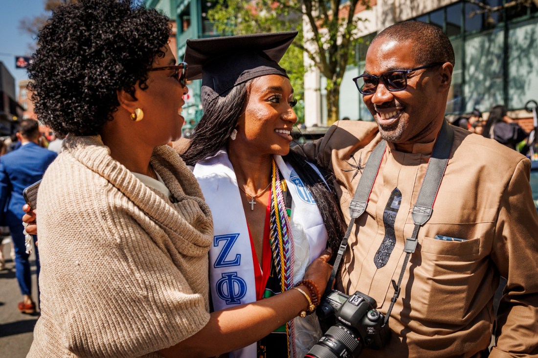 Northeastern graduate smiles and embraces family members outside Fenway Park on Commencement Day.