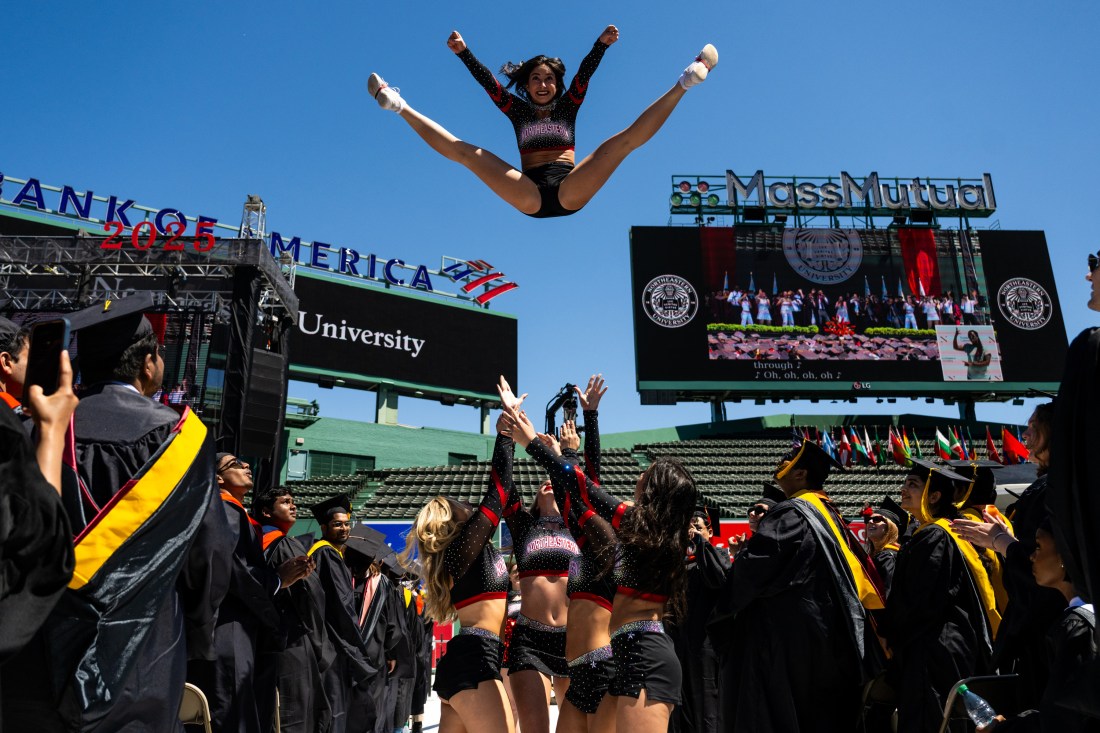 Northeastern cheerleader is thrown in the air during Commencement at Fenway Park.