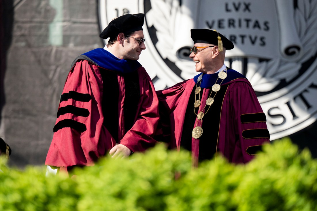 Elliot Grainge smiles while shaking hands with President Joseph E. Aoun on stage at Northeastern’s 2025 Commencement.