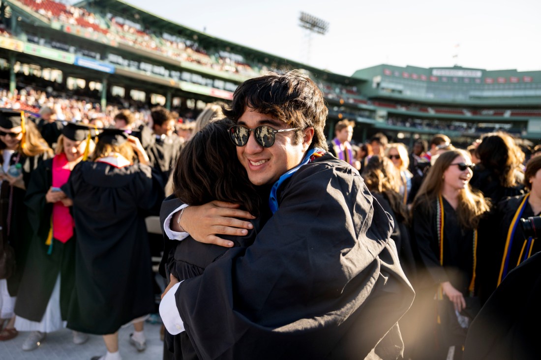 Graduates hug and celebrate during Northeastern’s 2025 commencement ceremony at Fenway Park.