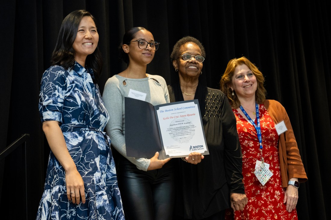 Four women, including Keila Da Cruz Sousa Rosario of Dearborn STEM Academy and Boston Mayor Michelle Wu, pose for a photo holding a certificate. They are smiling in front of a black curtain backdrop.