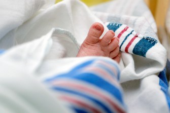 A baby's foot peeking out from underneath a blanket at a hospital.