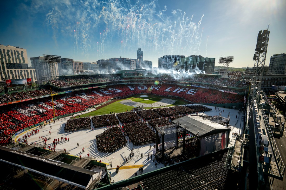 A wide view of Fenway Park filled with graduates and families during Northeastern’s 2025 commencement, with fireworks in the sky.