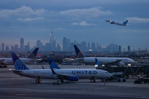 Airplanes on a runway with a city skyline in the background.