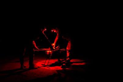 Two military men examine a drone, which is illuminated red.