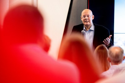 Usama Fayyad sitting on stage speaking into a microphone in front of audience members sitting and listening to him.
