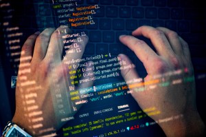 Two hands typing on a laptop. This image is overlaid with another that shows lines of code.