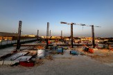 A construction site at sunset with cranes, scaffolding, and heavy equipment set up for a large-scale building project in Qatar.