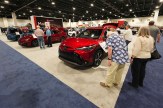 People examine vehicles on display at an auto show.