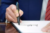 A close-up of Donald Trump&#039;s hand as he signs an executive order.