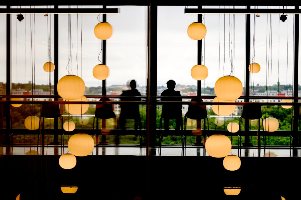 A person sits near a window surrounded by soft lighting and reflections.