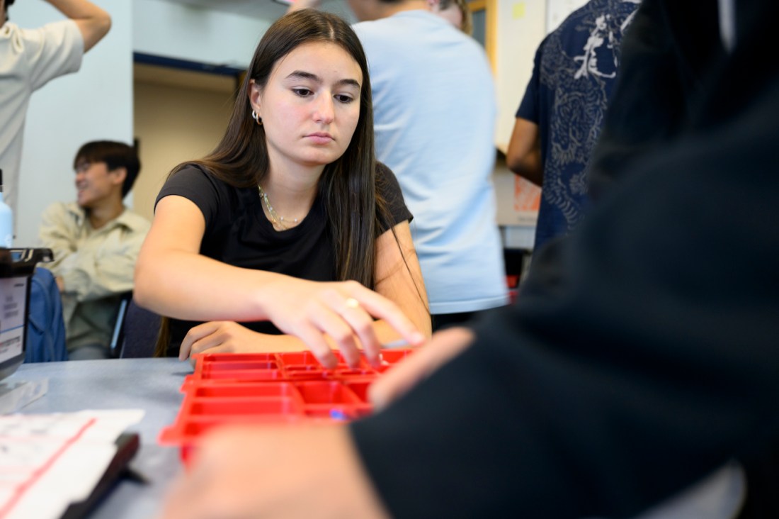A student reaching for LEGO pieces for their creation.