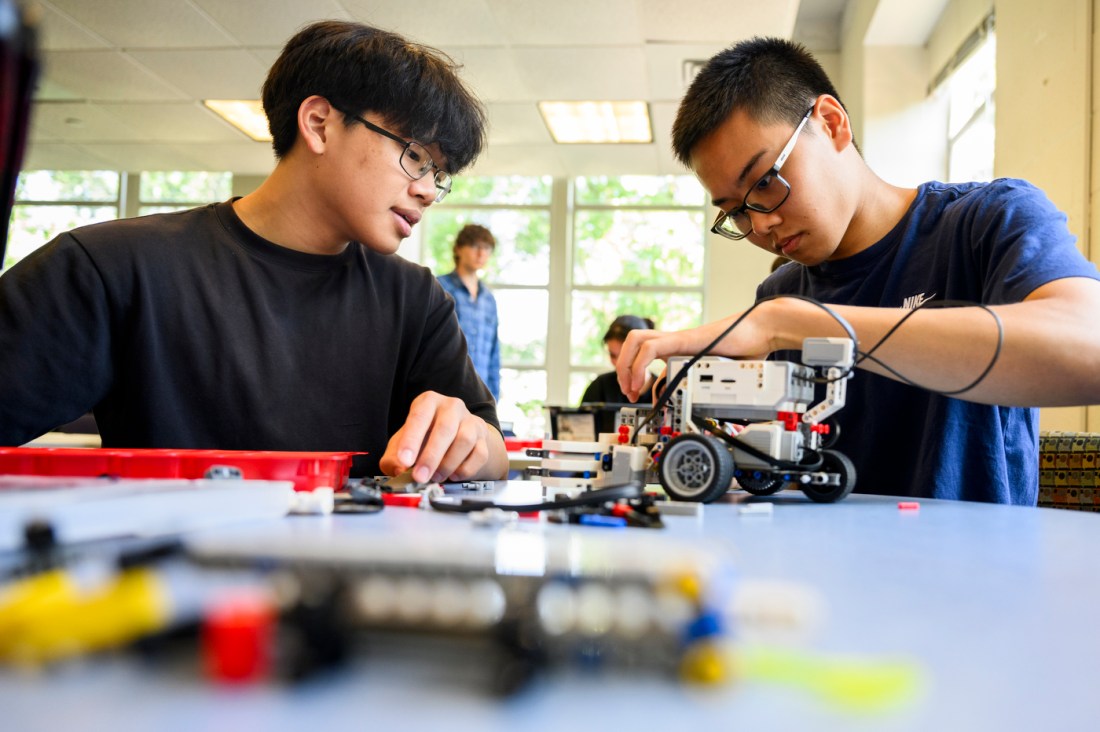 Two male students at work on several LEGO robot projects.