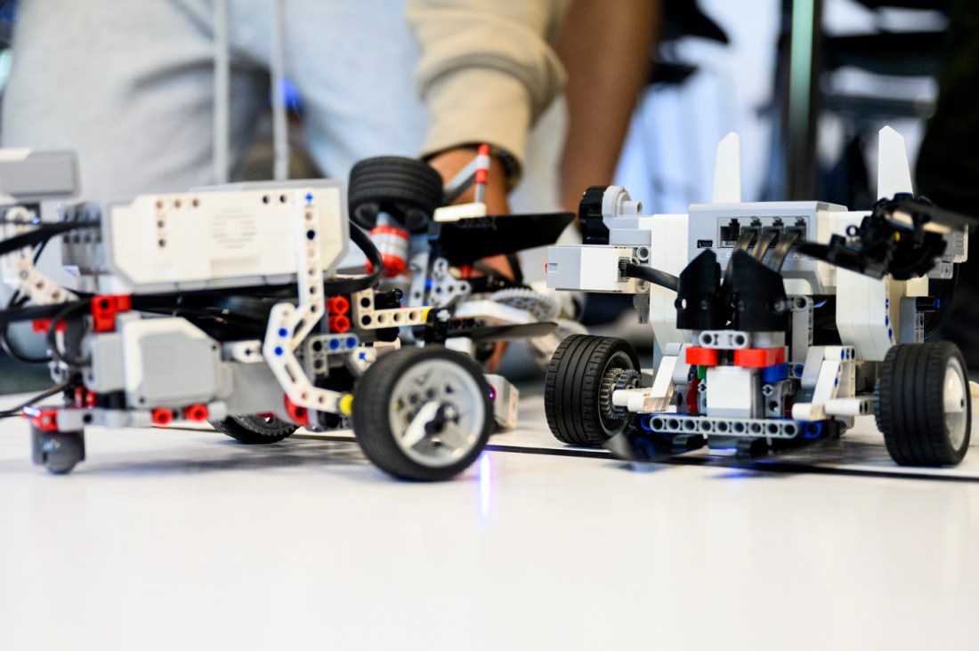 A closeup of two LEGO robots with wheels to move.