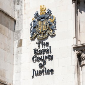 The exterior of a court building with a royal court of arms and 'The Royal Courts of Justice' on it.