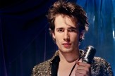 Jeff Buckley holding a microphone in front of a blue background.