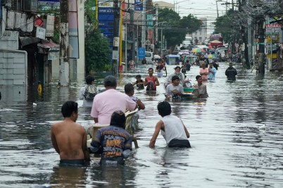 Residents in the Philippines are shown wading through a flooded road in the aftermath of a typhoon.