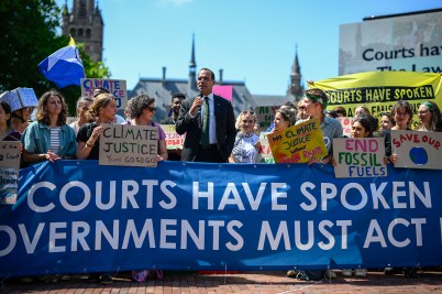 A group of climate protestors holding a blue sign urging governments to act.