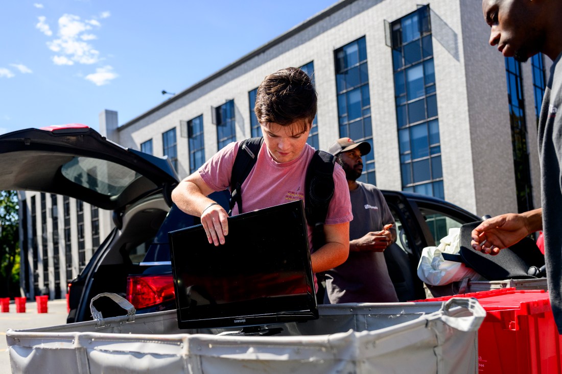 A student unloads a TV from a car.