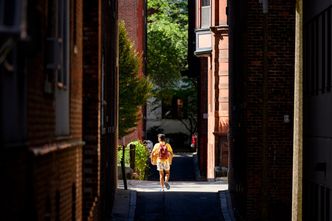 A student walks in between two buildings. 