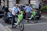 Men on Lime electric bicycles shown waiting at a traffic light.