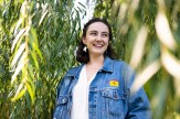 Isabelle Wood smiling while wearing a blue jean jacket between stalks of tall grass.
