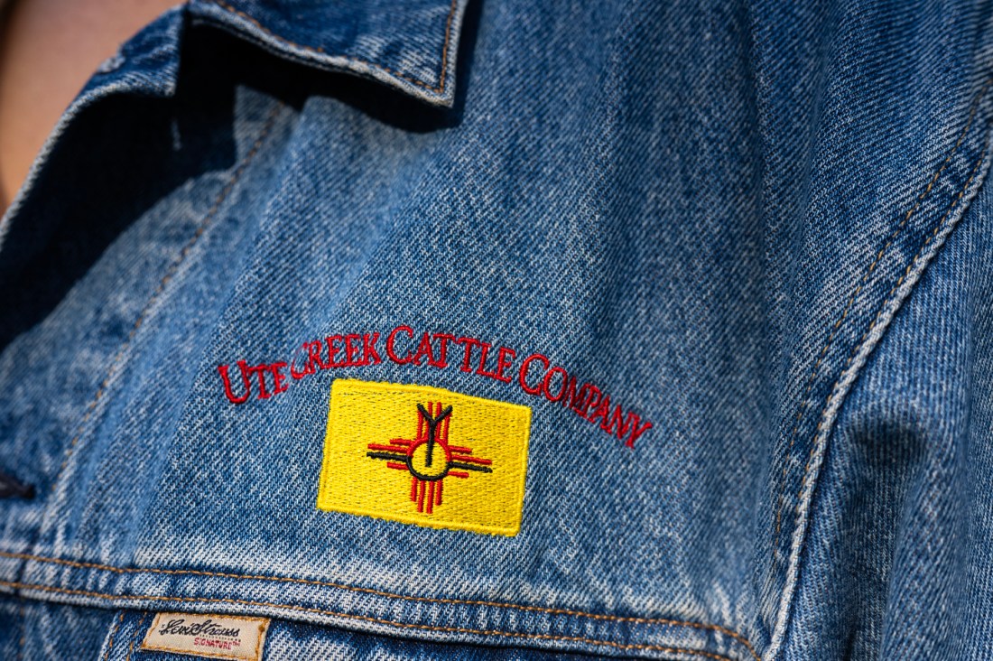 A close-up of the yellow "Ute Creek Cattle Company" logo on a blue jean jacket.