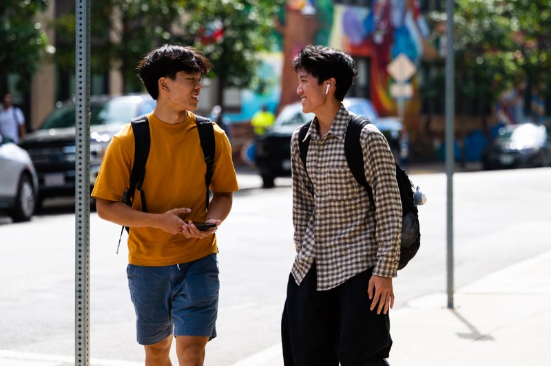 Two students greet each other outside.