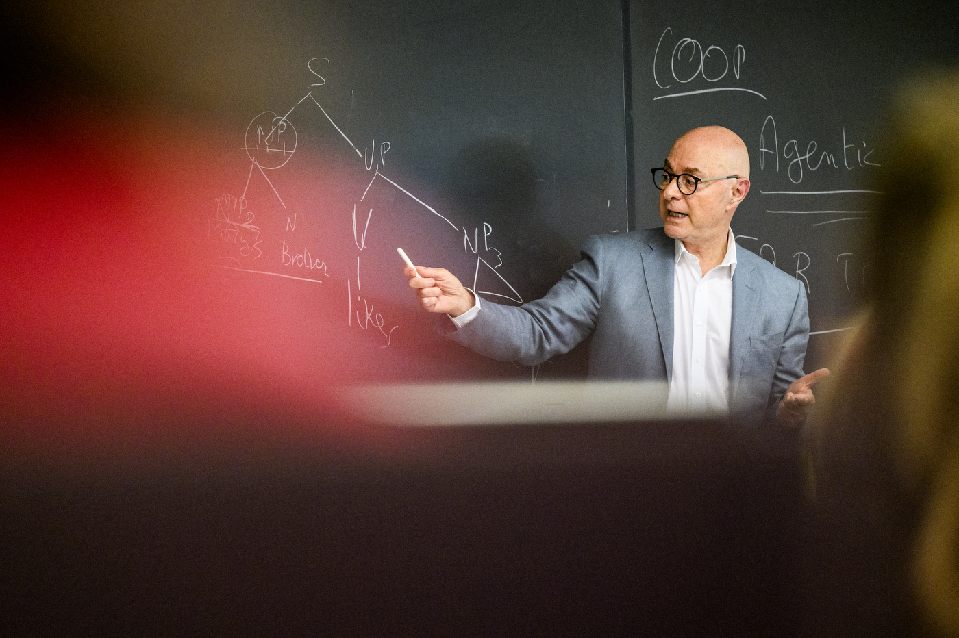 President Aoun, who is standing at a chalkboard and holding a piece of chalk, delivers a guest lecture to students.
